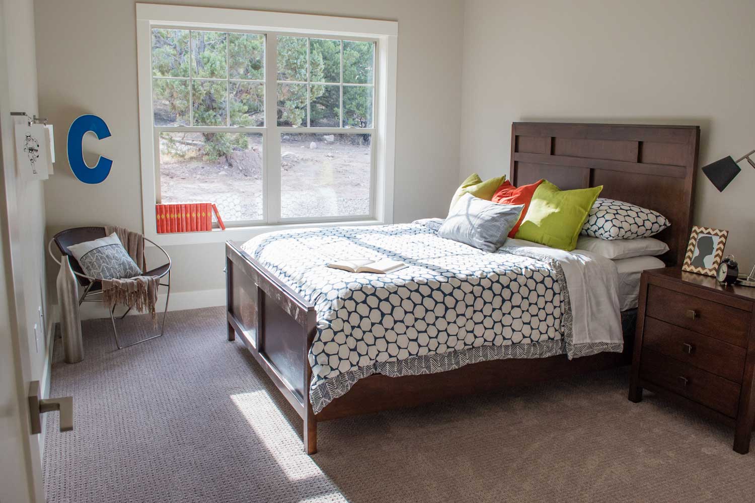 spare room with one queen size bed, dark wood bedframe, bright natural light come from main window that looks out into backyard