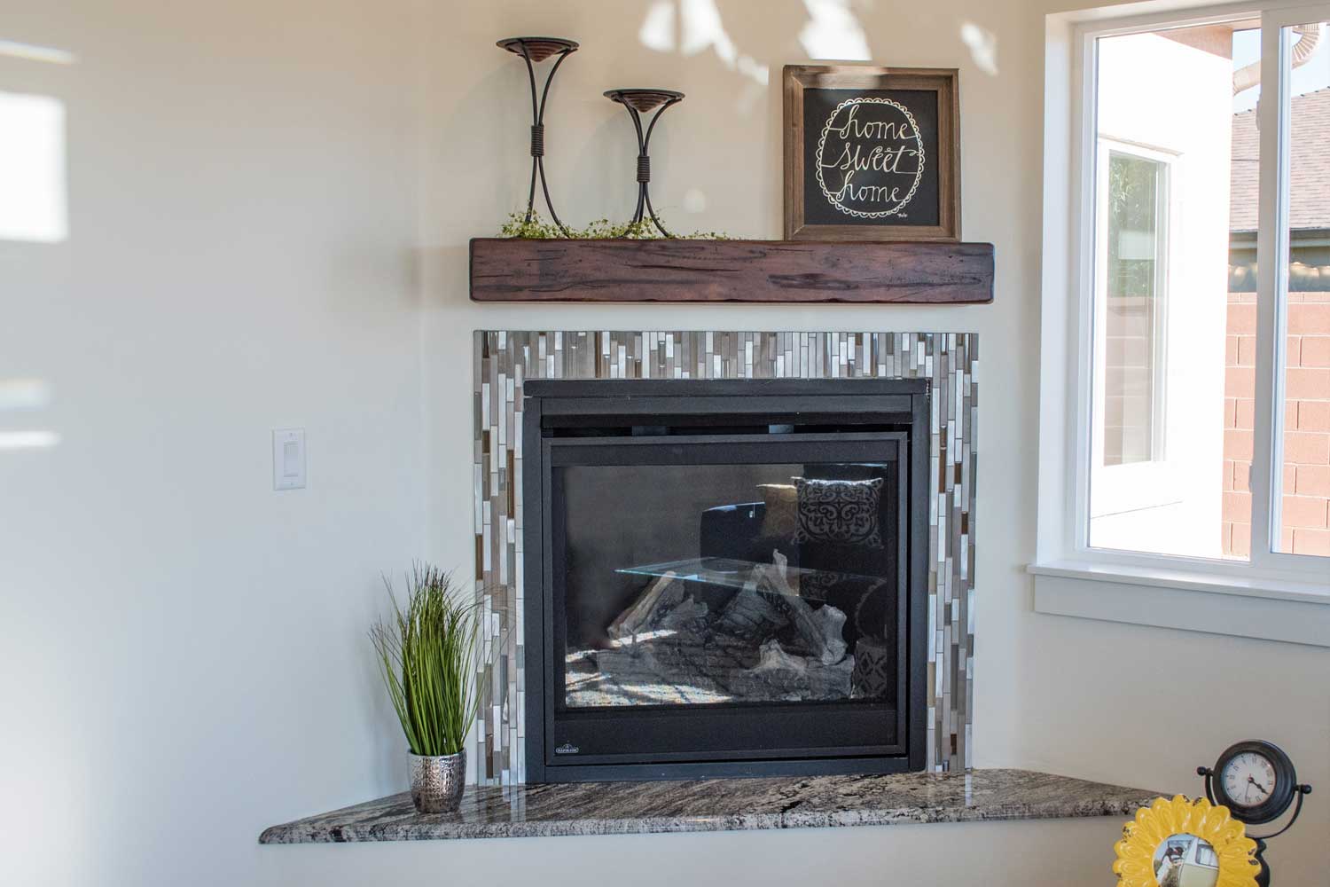 fireplace in the corner of the living room with home sweet home picture on top of the hearth