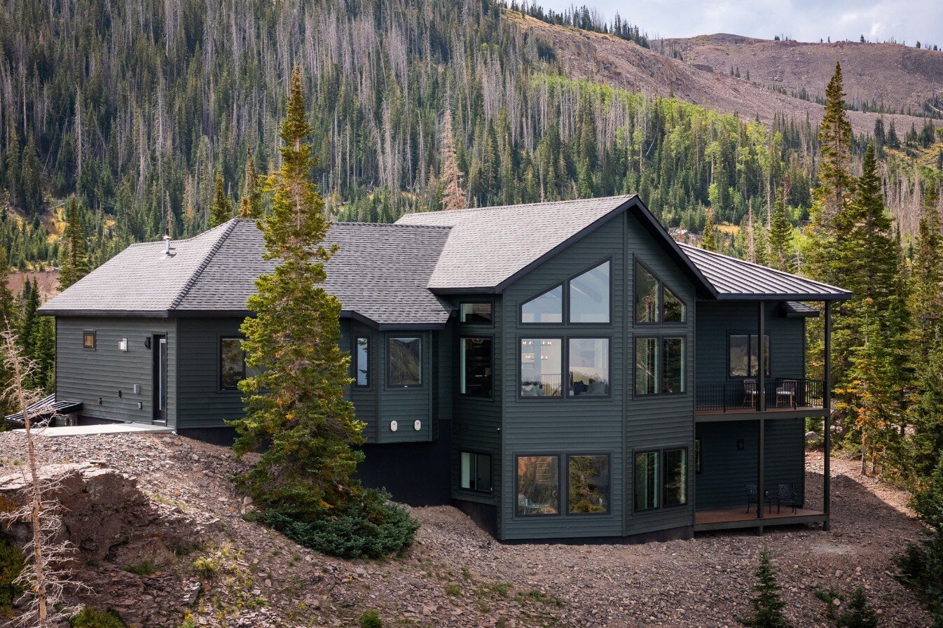 A stunning exterior view of a custom mountain lodge home in Brian Head, UT by Choice Builders, surrounded by lush evergreen trees and mountainous terrain