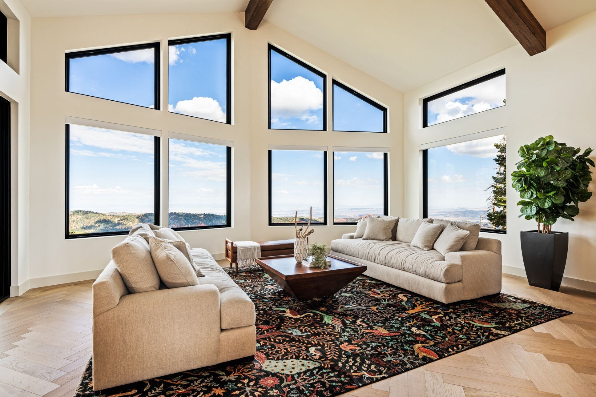 A sunlit living room with floor-to-ceiling windows overlooking a scenic mountain view in a custom mountain lodge home in Brian Head, UT by Choice Builders