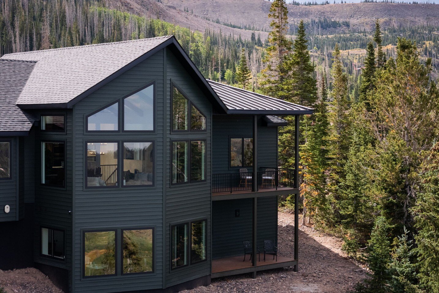 Back view of a custom mountain lodge home in Brian Head, UT by Choice Builders, surrounded by lush forest and scenic mountains