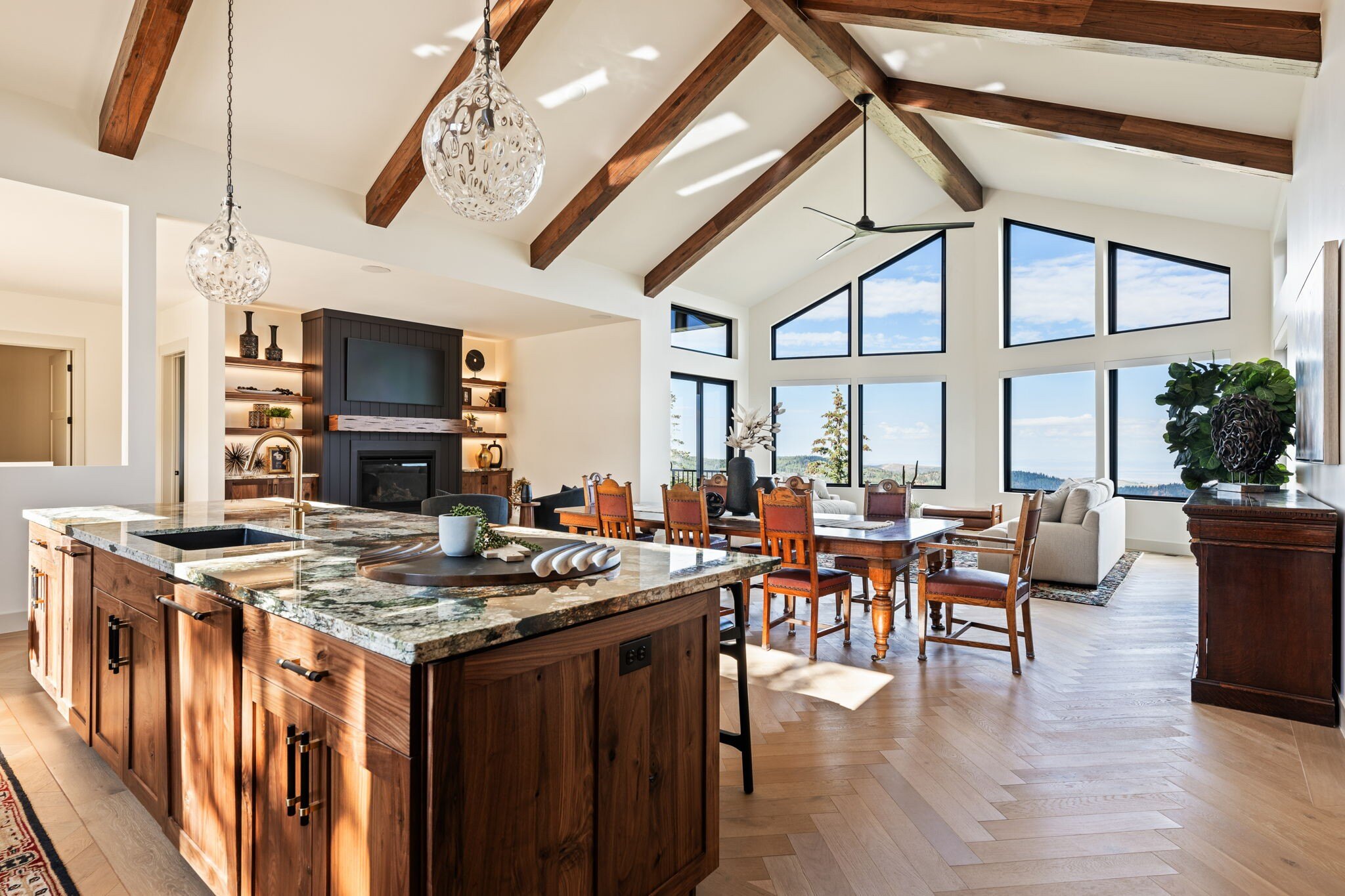 Bright and open kitchen and living area with wooden beams, elegant lighting, and scenic mountain views in a custom mountain lodge home in Brian Head, UT by Choice Builders