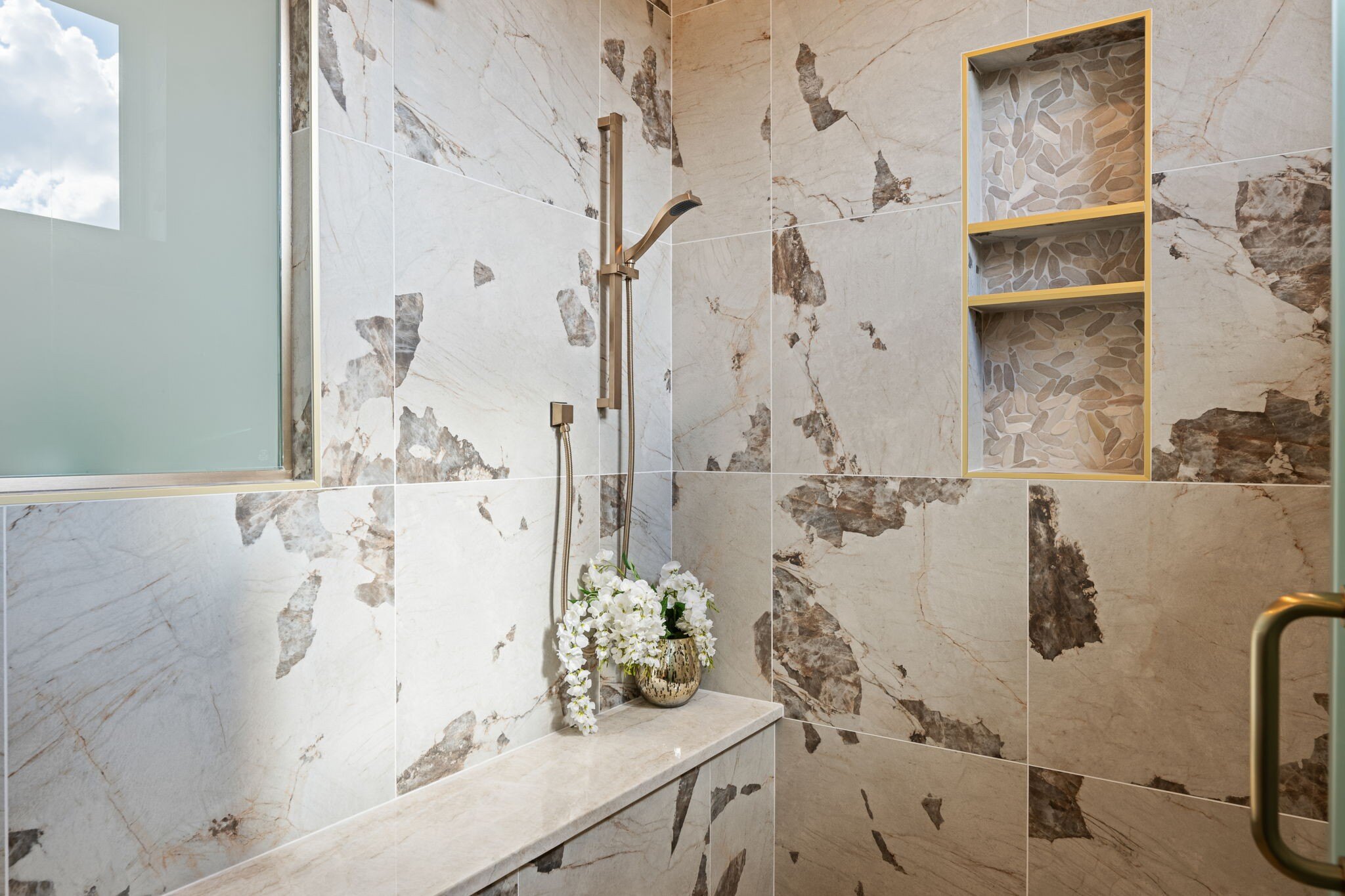 Elegant walk-in shower with natural stone tiles and built-in shelving, designed in a custom mountain lodge home in Brian Head, UT by Choice Builder