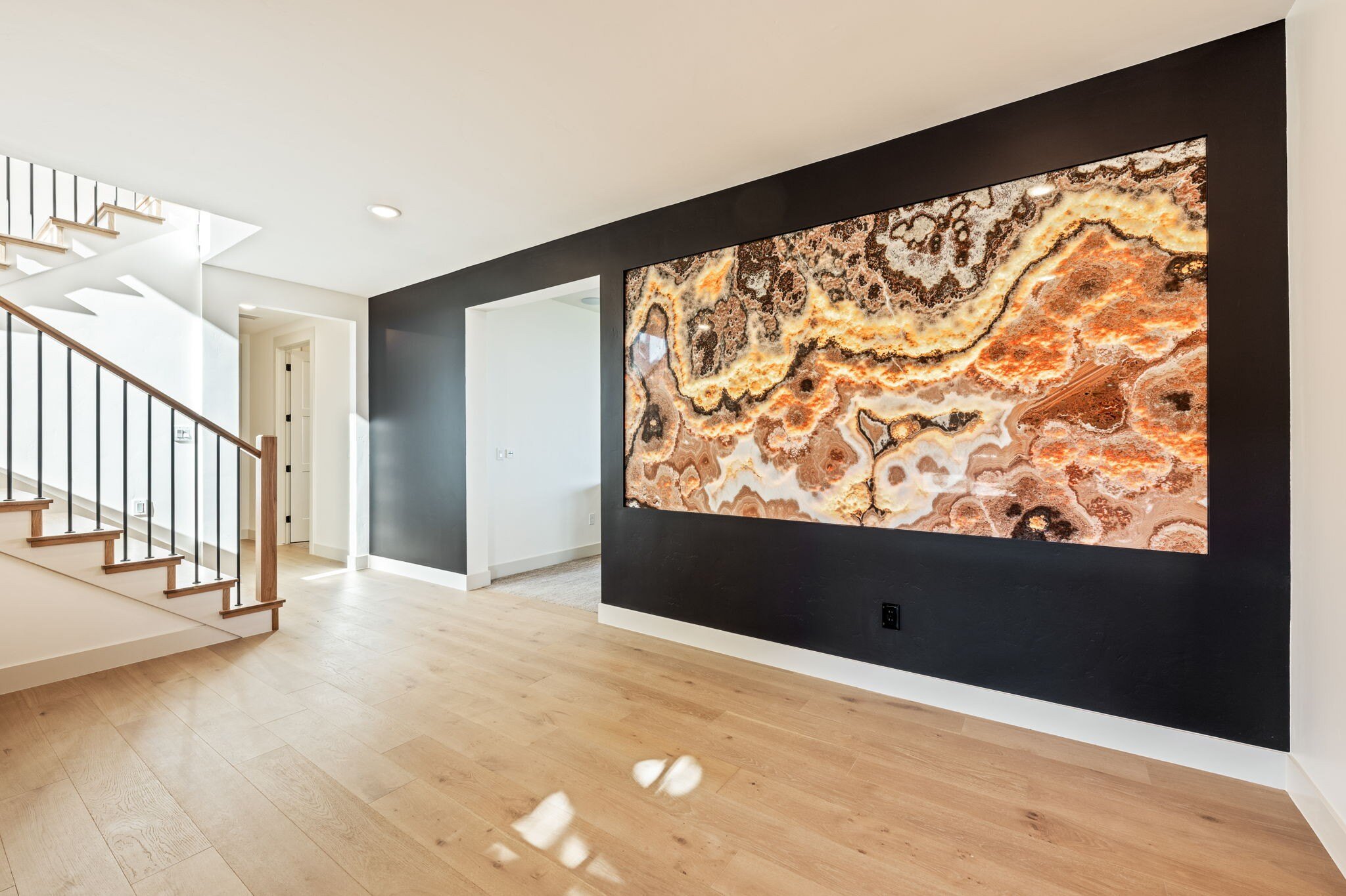 Interior view showcasing a modern staircase with natural wood steps and black railings, alongside a decorative granite piece in a custom mountain lodge home in Brian Head, UT by Choice Builders