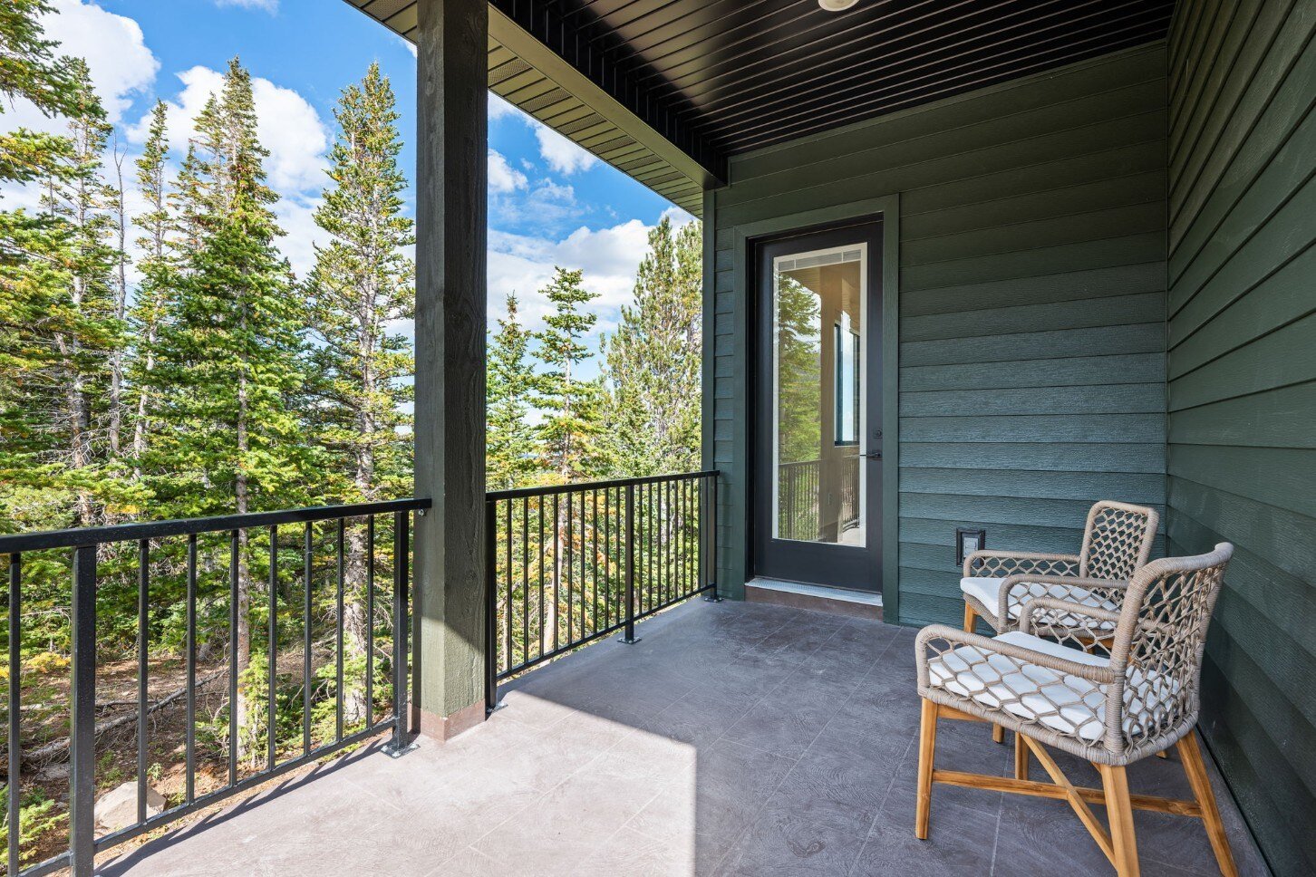 Inviting outdoor patio with seating, surrounded by tall evergreens, part of a custom mountain lodge home in Brian Head, UT by Choice Builders