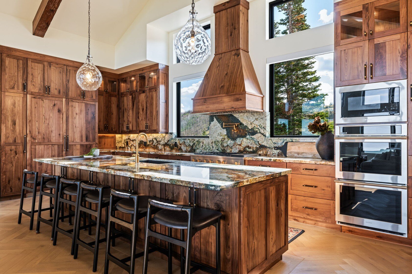 Luxury kitchen featuring a central island with a granite countertop, wooden cabinetry, and high-end appliances in a custom mountain lodge home in Brian Head, UT by Choice Builders