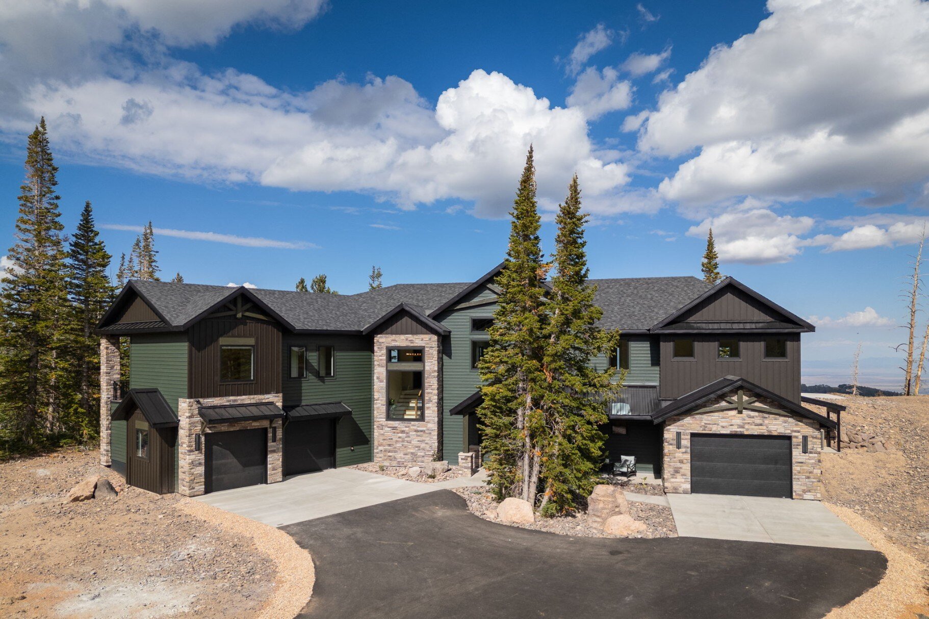 Stunning exterior view of a custom mountain lodge home in Brian Head, UT by Choice Builders, featuring dark wood siding and a stone facade