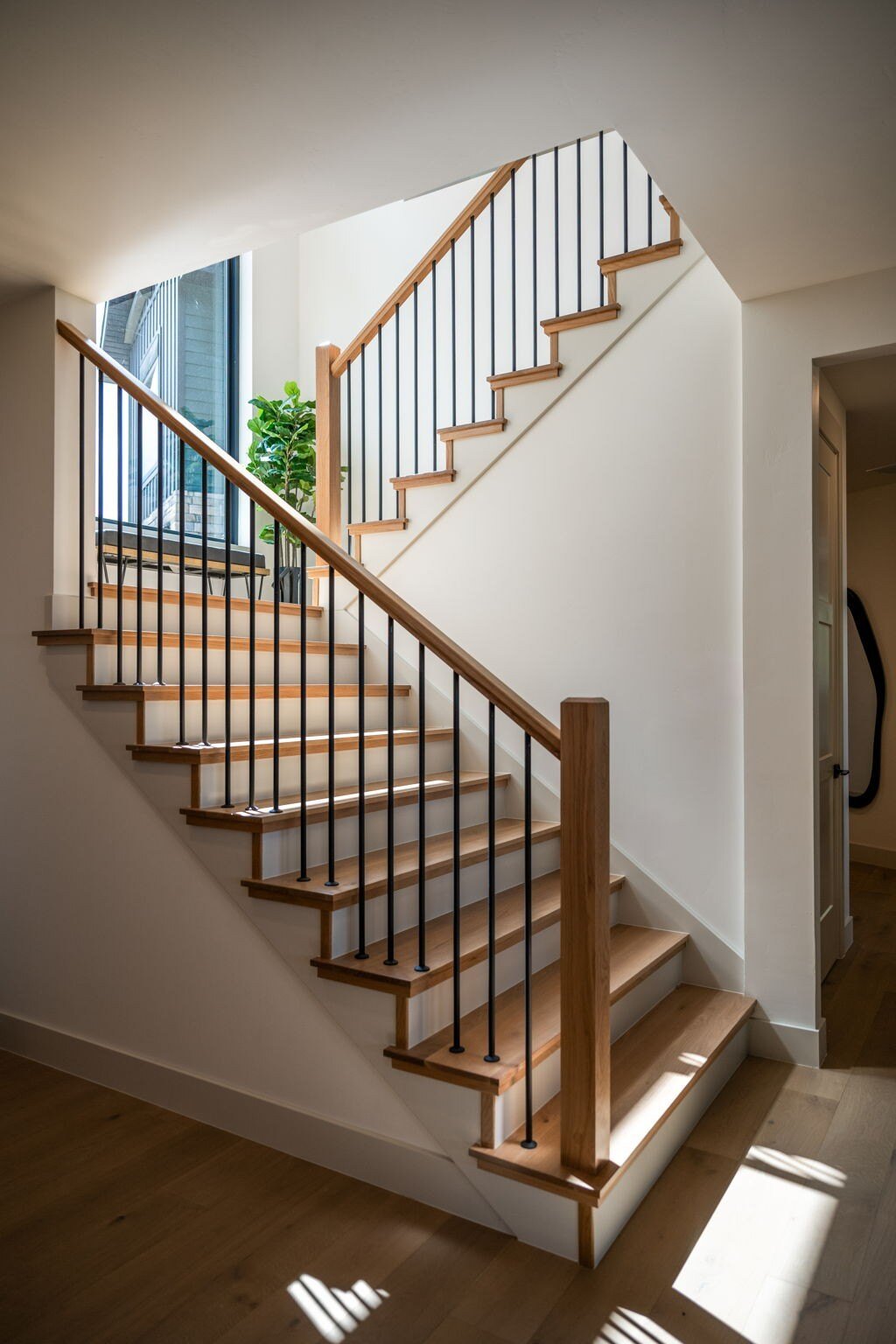 Wooden staircase with black metal railings, bathed in natural light in a custom mountain lodge home in Brian Head, UT by Choice Builder