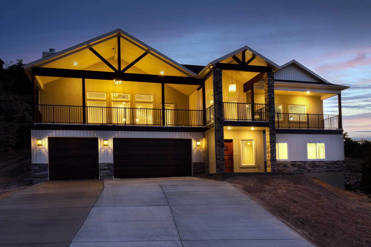 Front exterior of two story custom home featuring wrap around deck and three car garage