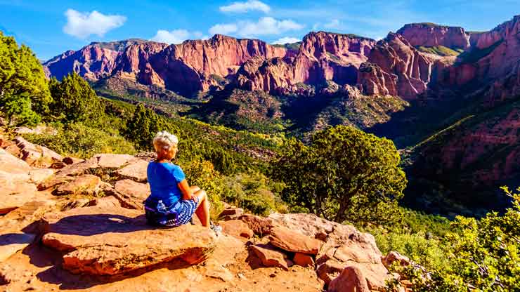 Senior woman enjoying the view of the Red Rock Mountains of the Kolob Canyon part of Zion National Park, Utah, United Sates. Viewed from the Timber Creek Lookout at the top of East Kolob Canyon Road